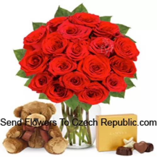 11 roses rouges avec quelques fougères dans un vase en verre accompagnées d'une boîte de chocolats importée et d'un mignon ours en peluche brun de 12 pouces de hauteur