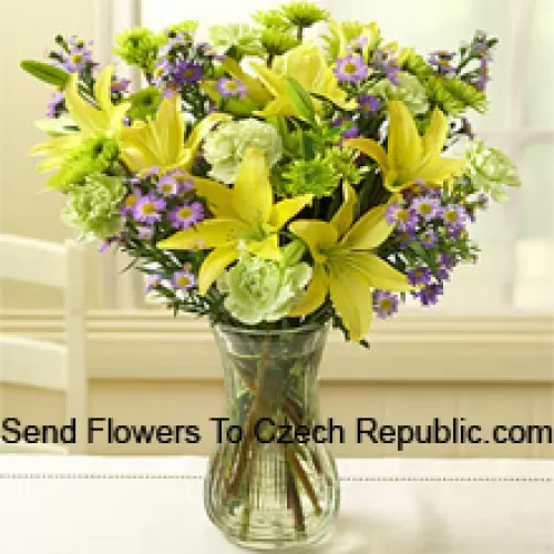 Lys jaunes et autres fleurs assorties disposés magnifiquement dans un vase en verre